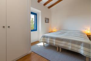 a white bedroom with a bed and a window at Mas Tinus - Palmera in Santa Cristina d'Aro
