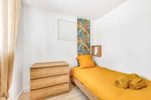 a small bedroom with a yellow bed and a dresser at Gite Barrail du Moulin in Bégadan
