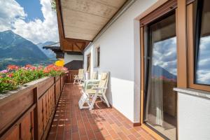 a balcony of a house with chairs and flowers at Gartenheim App Maria in Schenna