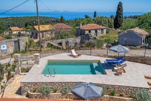 a swimming pool with two umbrellas and a house at Milia's House Ithaca in Vathi