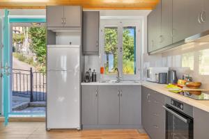 a kitchen with white cabinets and a white refrigerator at Milia's House Ithaca in Vathi