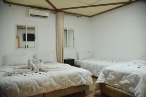 a room with two beds with white sheets and windows at Auberge Resto Agnaoue in Marrakesh