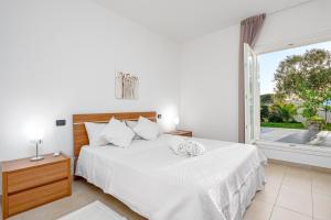 a bedroom with a white bed and a large window at Villa Marconi Apartment 5 in Golfo Aranci