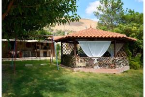 a gazebo with a white curtain in a yard at Apartment Vergina in Áyioi Dhéka