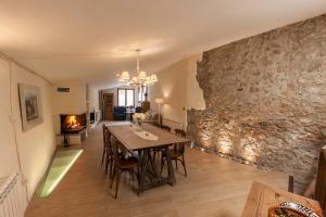 a dining room with a table and a stone wall at Cal Marti in Farena