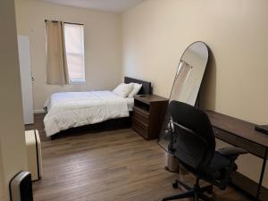 a bedroom with a desk and a bed and a mirror at Blessed Homes in East Orange