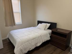 a bedroom with a bed and a nightstand with a white blanket at Blessed Homes in East Orange +1 photo