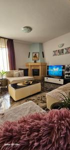 a living room with couches and a flat screen tv at Casa Aly Bușteni- Casa la cheie in Buşteni