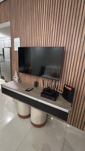 a desk with a large television on a wall at Biquinha - Praça 22 de Janeiro in São Vicente