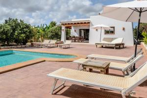 a villa with a swimming pool with chairs and an umbrella at Can Marsá de Baix in Santa Eularia des Riu