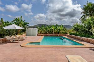 a swimming pool with a table and chairs and an umbrella at Can Marsá de Baix in Santa Eularia des Riu