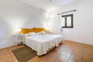 a white bedroom with a bed and a window at Can Marsá de Baix in Santa Eularia des Riu +20 photos