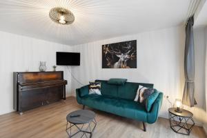 a living room with a green couch and a piano at Fewo Kerbe in Willingen