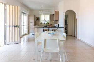 a white kitchen with a white table and chairs at Villa Clara in Gallina