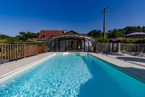a swimming pool with an archway and a house at Maison Iris in Castelnaud La Chapelle