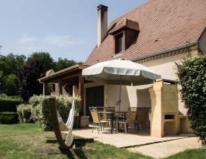 a patio with a table and an umbrella at Maison Iris in Castelnaud La Chapelle