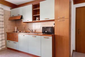 a kitchen with white cabinets and a microwave at cèsa Maria Suen in Canazei