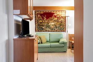 a living room with a green couch and a tapestry at cèsa Maria Suen in Canazei