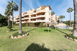 a large apartment building with palm trees and a yard at Penthouse 3-bedroom duplex in Mijas