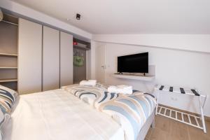 a living room with two beds and a flat screen tv at Lumeriam Sea Loft in Roccalumera