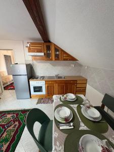 a kitchen with a table with plates and a refrigerator at Bugojno Avantura in Donjići