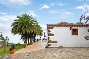 a white building with palm trees and a sidewalk at Casa Rural Ciso in Tijarafe