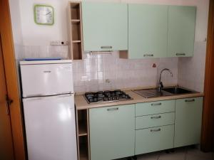 a kitchen with white cabinets and a white refrigerator at Euroholiday Village 3G in Lido di Jesolo