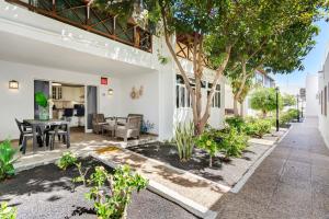 an outdoor patio with a table and chairs and trees at Plus Romance in Puerto del Carmen