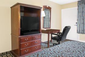 a hotel room with a television and a desk at Meridian Inn in Meridian +9 photos