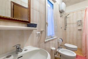 a bathroom with a sink and a toilet and a window at Sciabattica - Lacona in Lacona