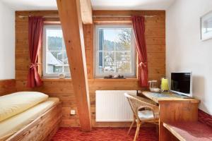 a bedroom with a bed and a desk with a computer at Gästehaus Krone in Sankt Georgen im Schwarzwald