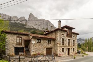 an old stone house with mountains in the background at Casa Rural El Agero in Cabañes