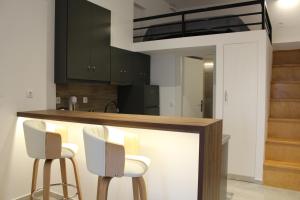 a kitchen with black cabinets and white bar stools at Kamara Studios in Alinda