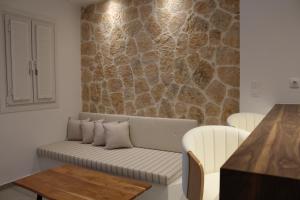 a couch in a living room with a stone wall at Kamara Studios in Alinda +7 photos
