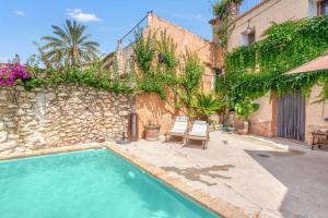 a house with a swimming pool next to a stone wall at Ca la Pasita 26 in Beniali