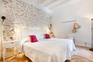 a bedroom with two beds and a stone wall at Ca la Pasita 26 in Beniali +28 photos