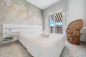 a bedroom with a large white bed and a chair at Apartment with spa and bbq in El Vendrell