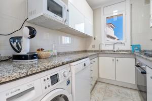 a white kitchen with a sink and a dishwasher at Apartment with spa and bbq in El Vendrell
