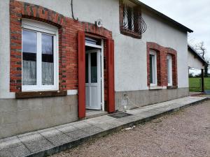 a brick house with a white door and windows at Le Gite du Champ de la Croix in Subligny