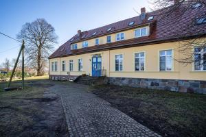 a yellow house with a red roof and a cobblestone driveway at Gutshaus Meerzauber in Altenkirchen