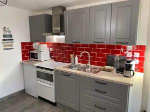 a kitchen with a sink and a red brick wall at La Noisette in Équemauville