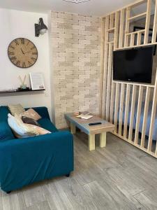 a living room with a blue couch and a tv at La Noisette in Équemauville
