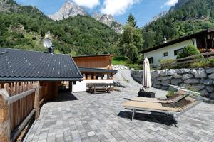 a patio with two chairs and an umbrella and a building at Mountain Chalet Tribulaun Pflersch in Colle Isarco