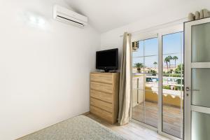 a room with a tv and a door with a balcony at Exclusive Sonemar in Maspalomas