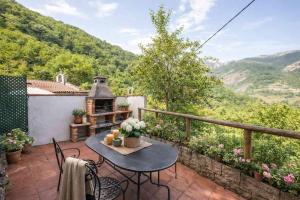 a patio with a table and chairs and mountains at El Ablanu, jacuzzi y vistas in Proaza