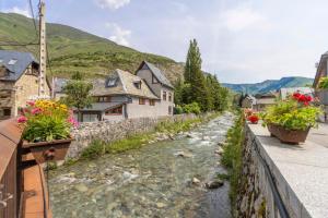 a river in a town with houses and flowers at Casa aranesa en centro de Arties in Arties