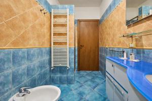 a bathroom with blue tiled walls and a sink at Casa Martina in Sassetta +12 photos