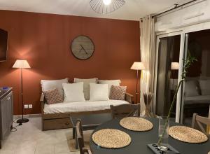 a living room with a couch and a clock on the wall at Maison en Drôme Provençale in Nyons