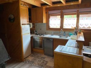 a kitchen with wooden cabinets and a white refrigerator at Chalet 6p Confort - Le chevreuil in Verchaix