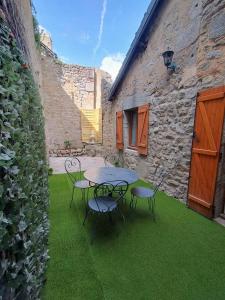 a patio with a table and chairs on the grass at Gite cozy, Parc naturel du Morvan in Lormes